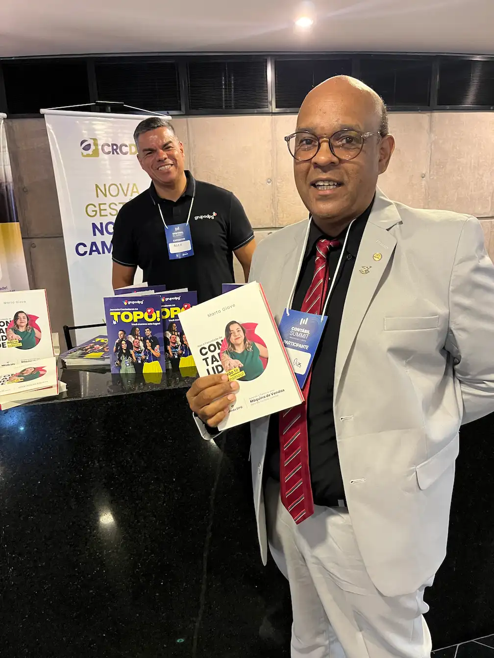 Leitor com o livro no estande do Grupo DPG