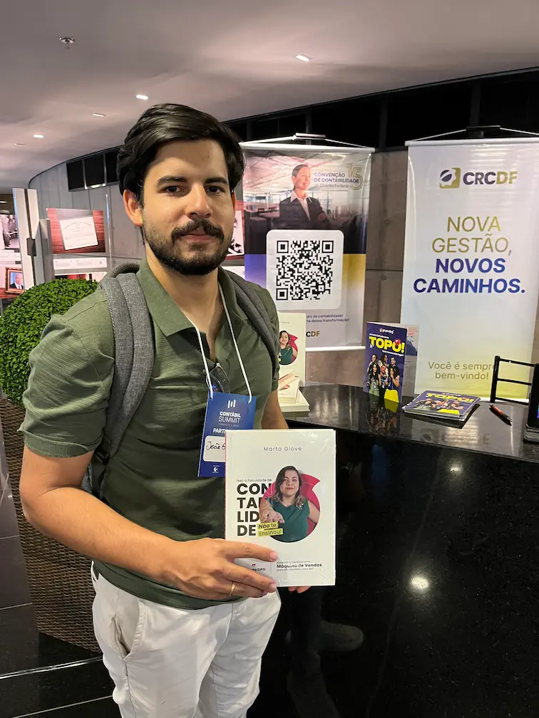 Leitor com o livro na mesa de vendas do evento